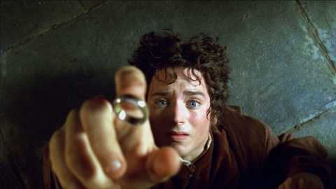 Frodo Baggins on the floor reaching for the ring of power as it falls.