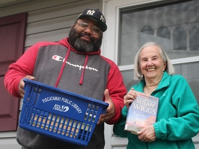 Person holding basic of books and customer holding up a book cover