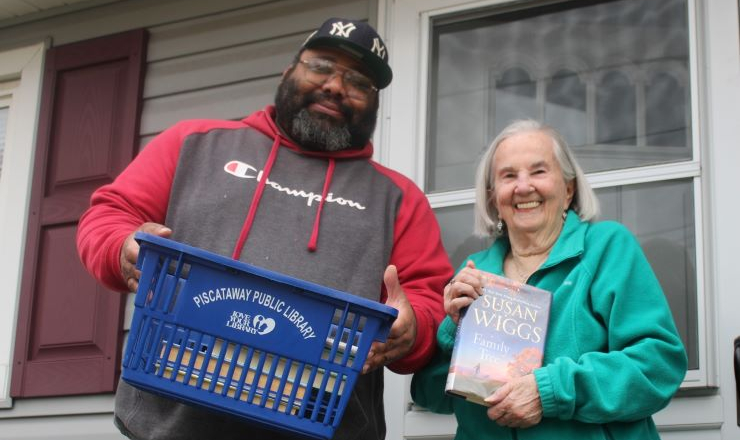 Home delivery person holding basket of Piscataway Public Library books